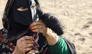 Donna omanita intenta a filare la lana Una donna omanita in vesti tradizionali mentre fila la lana