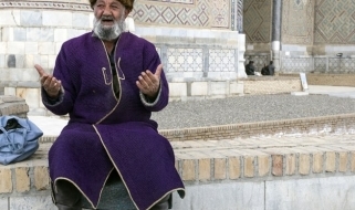 Un uomo ritratto con le vesti tradizionali nella piazza pubblica Registan a Samarcanda